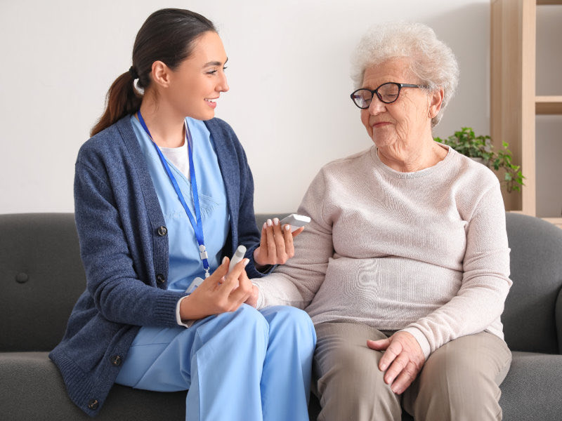 A caregiver assisting an old woman
