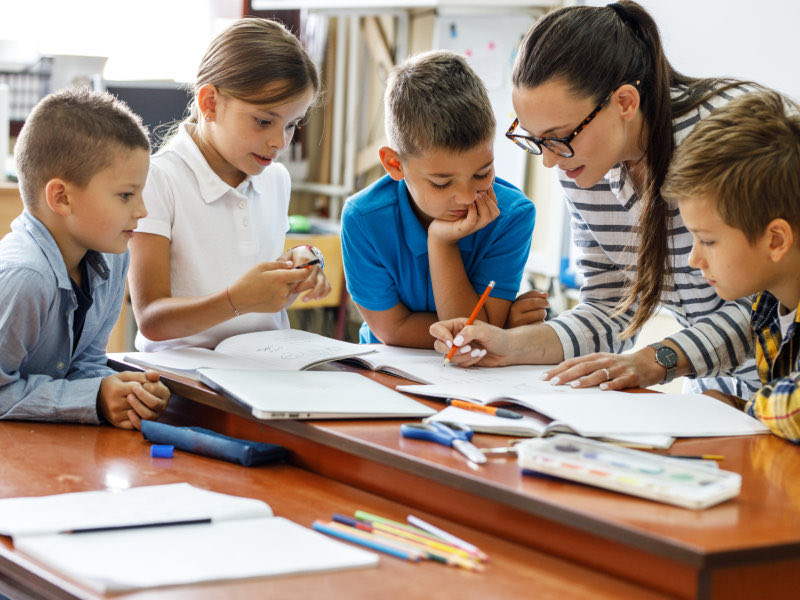 kind female teacher spends time with her elementary school students